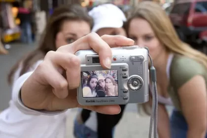 Persona revisando fotos antiguas en una cámara digital de los 2000, con expresion de sorpresa al descubrir recuerdos perdidos