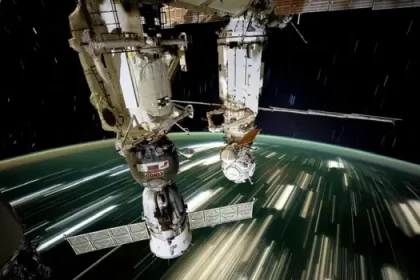 Estación Espacial Internacional orbitando la Tierra con paneles solares desplegados, vista desde la Cúpula con la Tierra al fondo iluminada por el sol