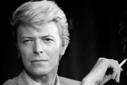 David Bowie con traje de Ziggy Stardust en un escenario iluminado, símbolo de su reinvención artística y genialidad musical
