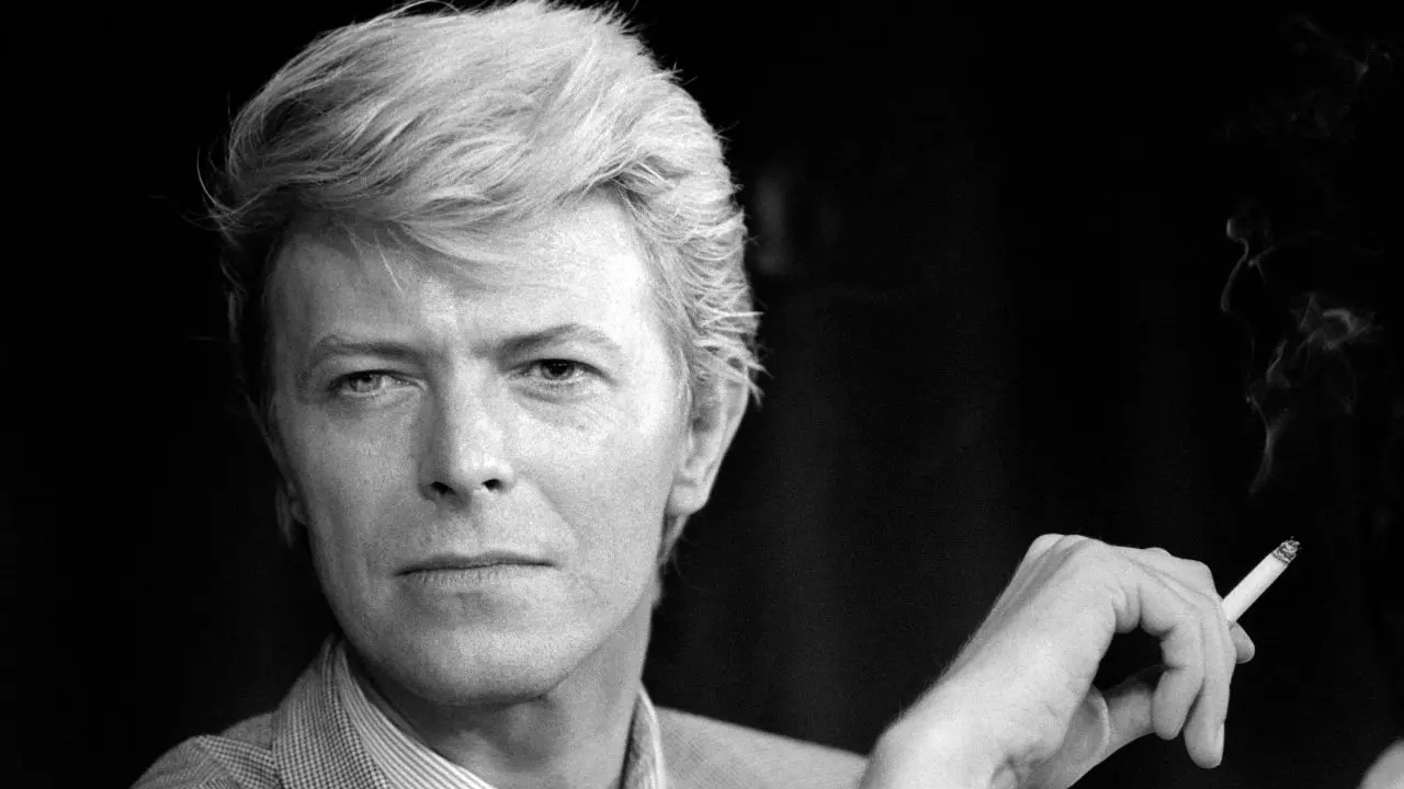 David Bowie con traje de Ziggy Stardust en un escenario iluminado, símbolo de su reinvención artística y genialidad musical