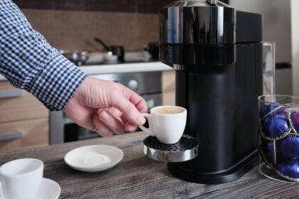 Caja de cápsulas McCafé Premium Roast K-Cup con etiqueta de descafeinado pero que contienen cafeína, junto a taza de café humeante