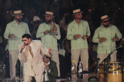 Bad Bunny en el escenario del Super Bowl LX con un Flamboyán de fondo, simbolizando la fusión de culturas latinas en un show histórico