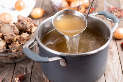 Olla con caldo de huesos gelatinizado tras 12 horas de cocción lenta, mostrando huesos de caña, rodilla y costilla en capas nutritivas