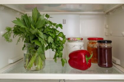 Hierbas frescas como perejil y cilantro en recipiente con agua y film transparente, técnica de chef Michelin para evitar oxidación y deshidratación
