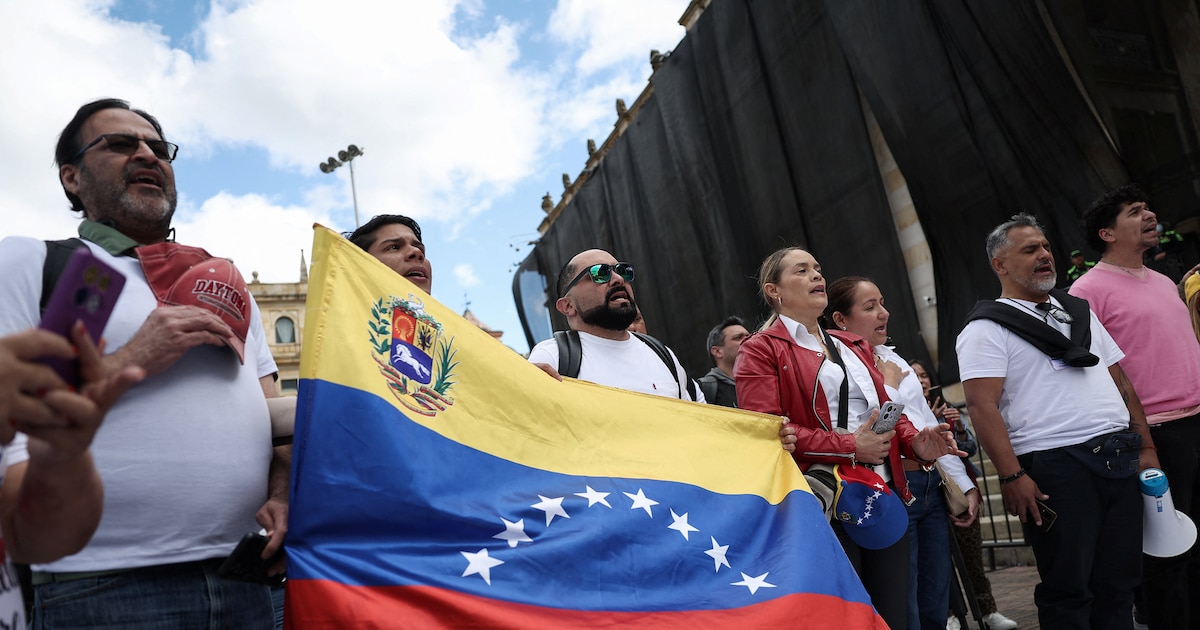 Manifestantes en Plaza Bolívar piden liberación de presos políticos en Venezuela, con carteles que exigen 'Democracia ya' bajo un cielo nublado