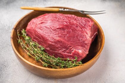 Familia revisando cortes de carne como aguja o lomo en un supermercado, elegibles para reembolso de $87.5 millones por sobreprecios