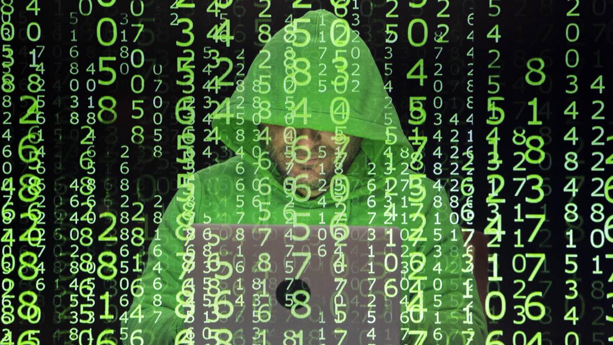 Persona revisando correo sospechoso de Booking falso con alerta de fraude digital y voz clonada en pantalla de computador