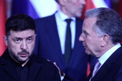 Reunión diplomática en Berlín con Zelensky y enviados de EE.UU. discutiendo garantías de seguridad para Ucrania frente a Rusia, con mapa de Donbás al fondo
