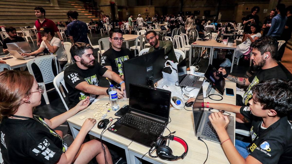 Equipo de desarrolladores trabajando en un prototipo de videojuego durante el Global Game Jam, con pantallas mostrando código y diseños en tiempo real