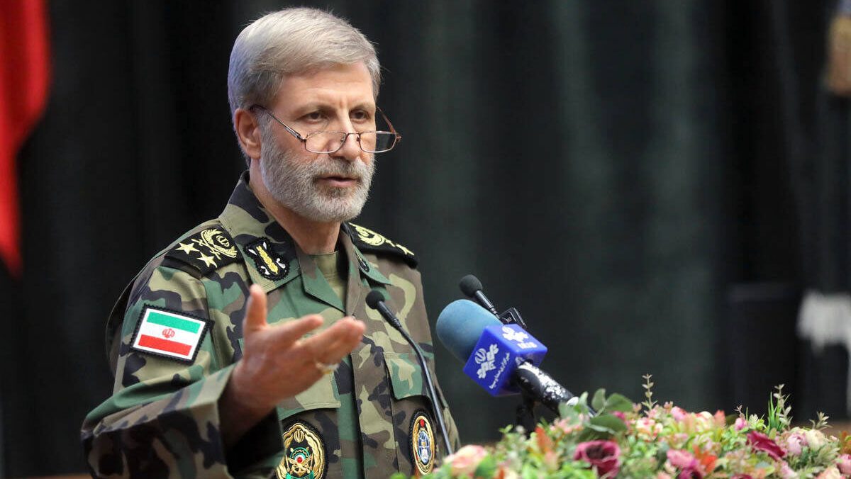 General iraní Amir Hatami en postura de alerta militar con mapa de Oriente Medio y flota estadounidense desplegada en el Golfo Pérsico