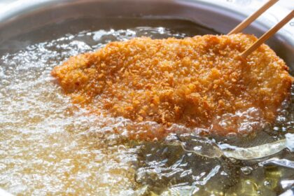 Alimentos crujientes recién fritos en aceite caliente a 180°C, escurridos con técnica profesional para eliminar exceso de grasa