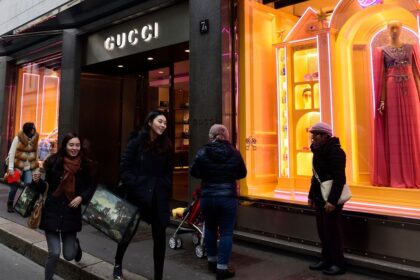 Ejecutivo de lujo analizando datos de IA en una pantalla holográfica con diseños de moda futuristas y gráficos de tendencias de consumo premium