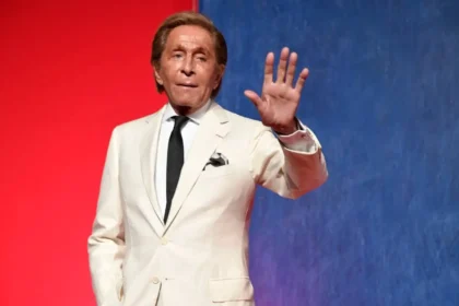 Retrato en blanco y negro de Valentino Garavani con un vestido rojo icónico de su colección, símbolo de su legado en la moda italiana