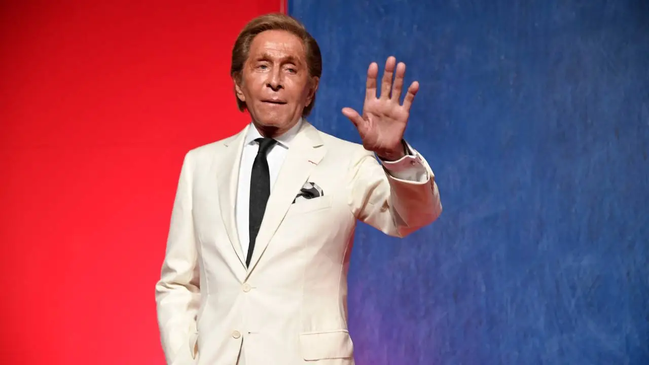 Retrato en blanco y negro de Valentino Garavani con un vestido rojo icónico de su colección, símbolo de su legado en la moda italiana