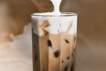 Taza de café helado con espuma de proteína y decoración de matcha, ideal para energía estable y saciedad