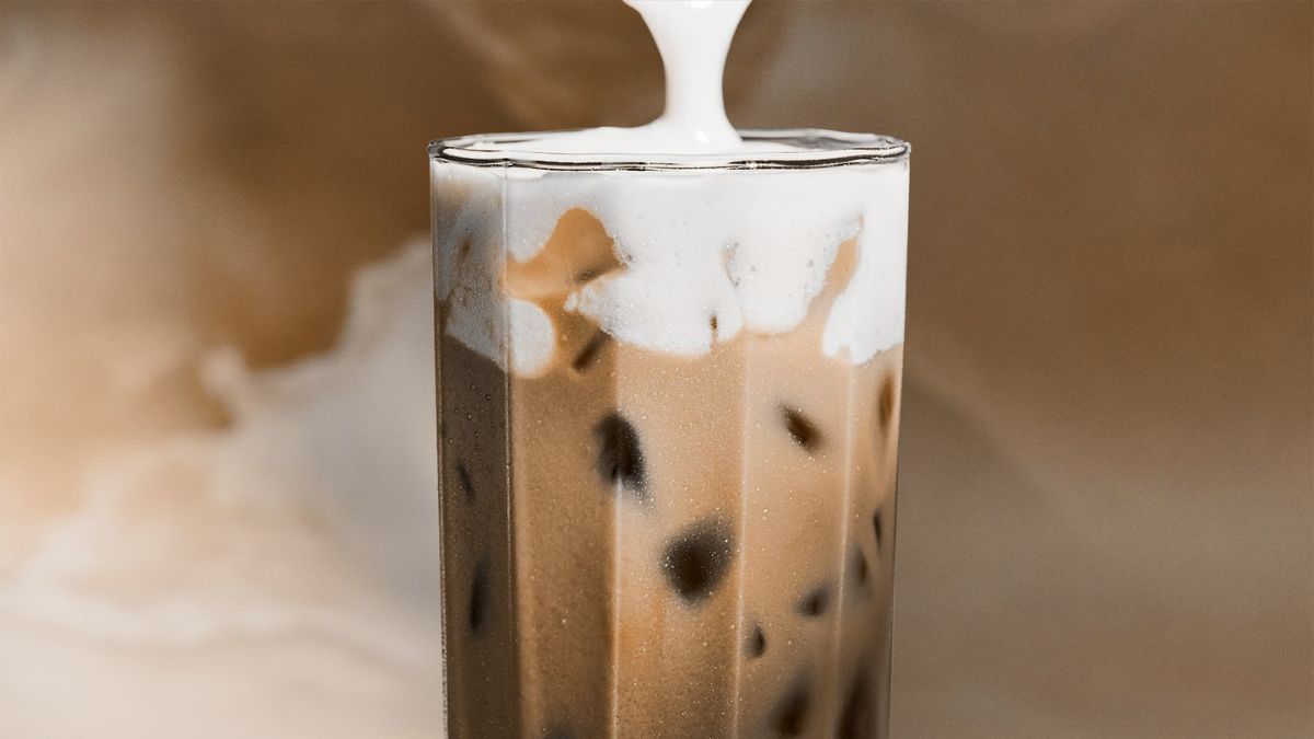 Taza de café helado con espuma de proteína y decoración de matcha, ideal para energía estable y saciedad