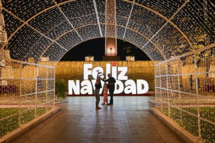 Árbol de Navidad de plástico descuidado en plaza de Caracas bajo sol tropical, símbolo de la Navidad forzada en Venezuela