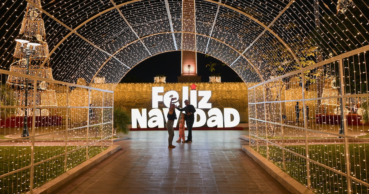 Árbol de Navidad de plástico descuidado en plaza de Caracas bajo sol tropical, símbolo de la Navidad forzada en Venezuela