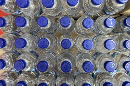 Jarra de agua destilada con tapa roja mostrando partículas negras en el fondo, señal de contaminación por filtros dañados o moho