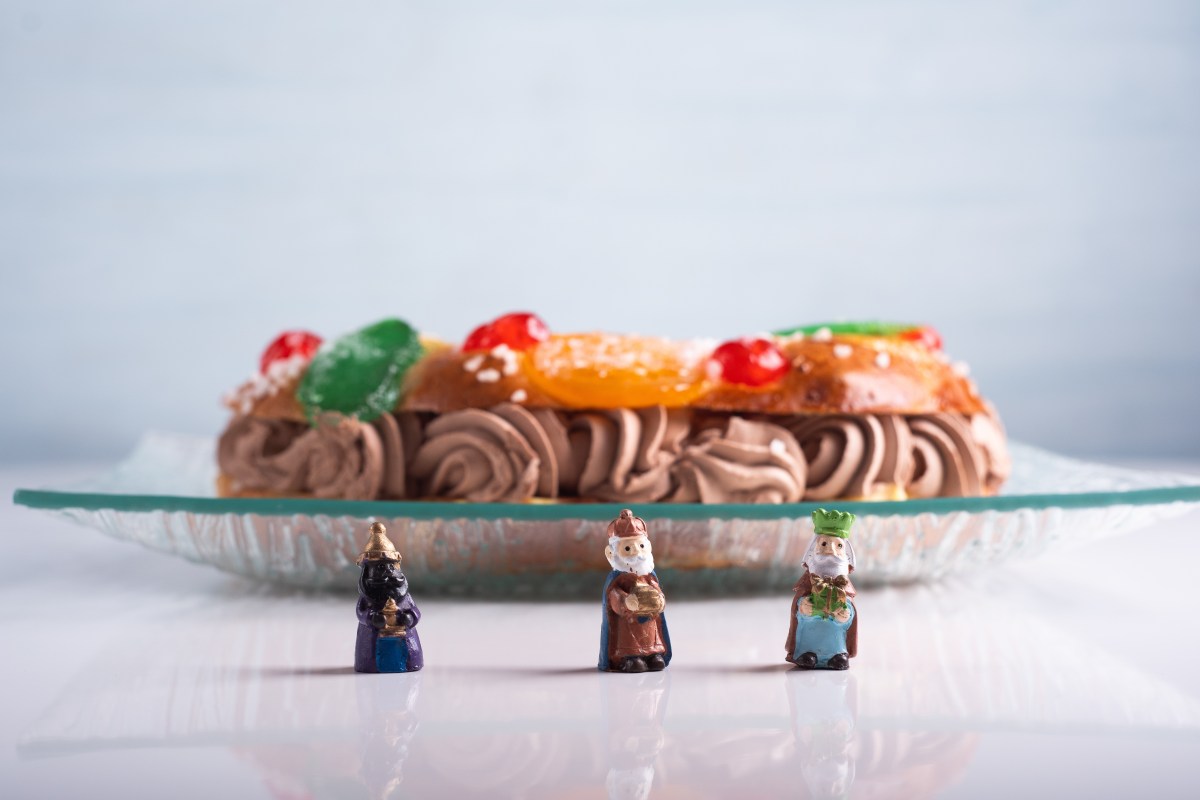 Roscón de Reyes artesanal con relleno de tarta de queso y decoración de frutas escarchadas, listo para servir en mesa navideña