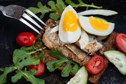 Plato de sardinas y huevos revueltos con pimiento rojo, cebolla morada y cilantro, rico en Omega-3 y colina para salud cerebral y muscular
