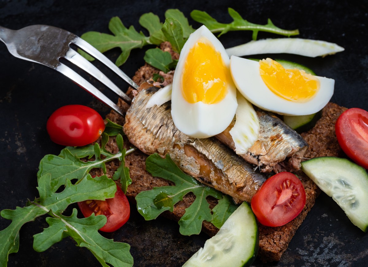 Plato de sardinas y huevos revueltos con pimiento rojo, cebolla morada y cilantro, rico en Omega-3 y colina para salud cerebral y muscular