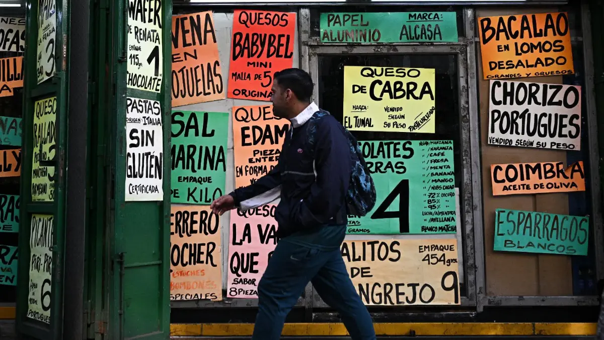 Mujer revisando precios en dólares en un supermercado venezolano con estantes semivacíos y billetes de bolívares devaluados en mano