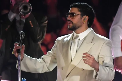 Bad Bunny en el escenario del Atanasio Girardot con traje beige oversize y sombrero de orejeras, interpretando éxitos ante un público con banderas de Puerto Rico y Colombia