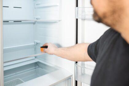 Mujer limpiando con cloro las paredes internas de un refrigerador para eliminar bacterias y biopelículas resistentes al frío