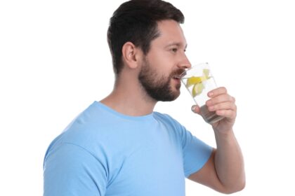 Vaso de agua con limón y sal marina sobre mesa de madera, simbolizando hidratación efectiva con minerales esenciales