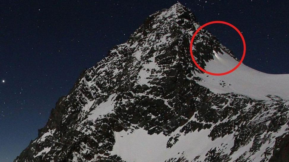 Montañista con equipo de escalada en la cumbre del Grossglockner bajo tormenta de nieve, reflejando el debate sobre negligencia en alpinismo