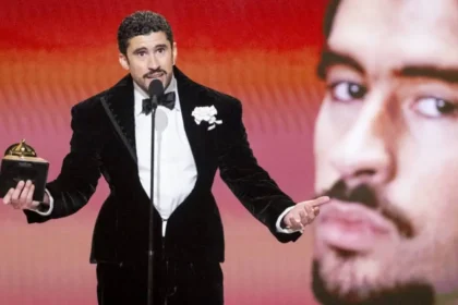 Bad Bunny con traje blanco en los Grammy 2024 levantando su premio mientras dice 'Fuera ICE' en apoyo a los inmigrantes