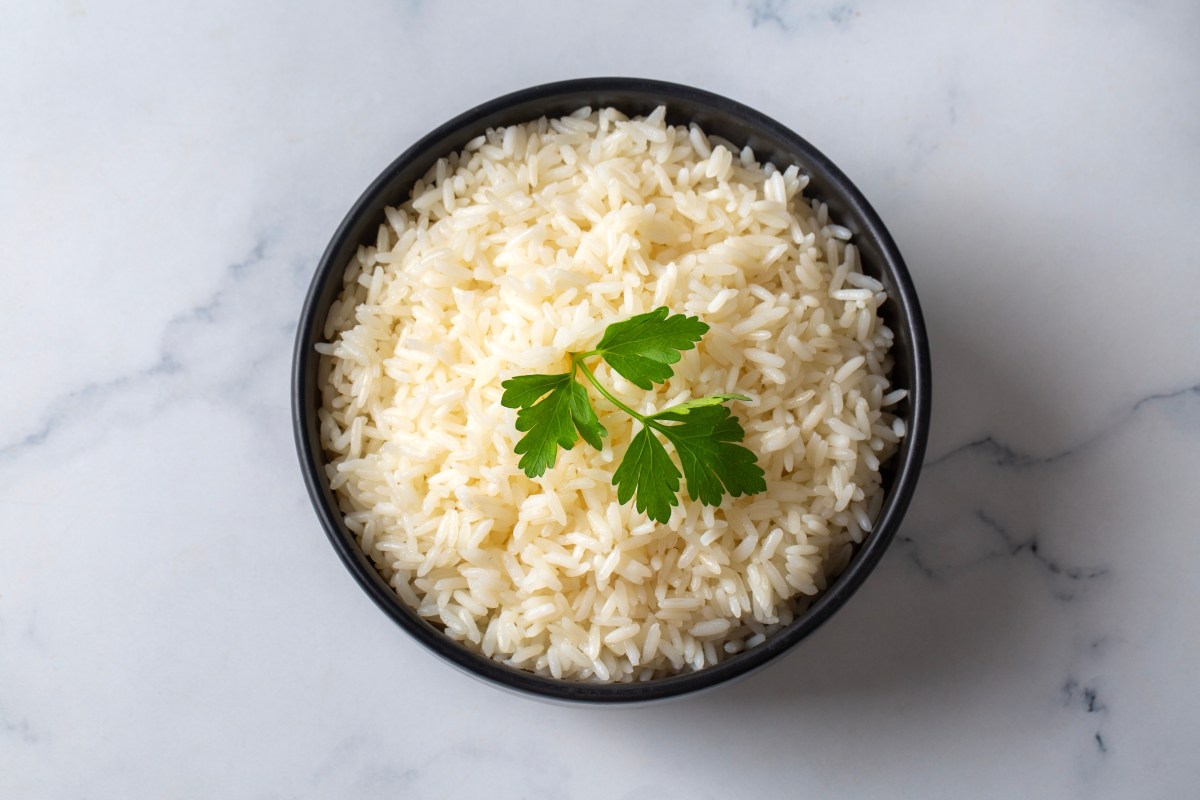 Arroz blanco cremoso con granos sueltos y brillantes, cocinado con caldo de pollo y mantequilla en una cacerola de acero inoxidable