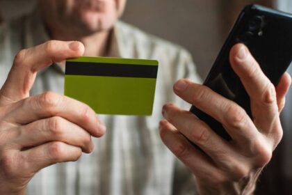 Persona con teléfono en mano recibiendo llamada sospechosa de estafa bancaria mientras revisa su app con alerta de transferencia fraudulenta
