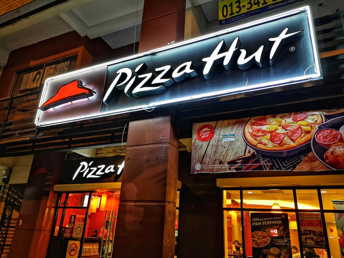 Exterior de un local de pizza con letrero apagado, simbolizando el cierre de 250 restaurantes en EE.UU. como parte del plan 'Hut Forward'