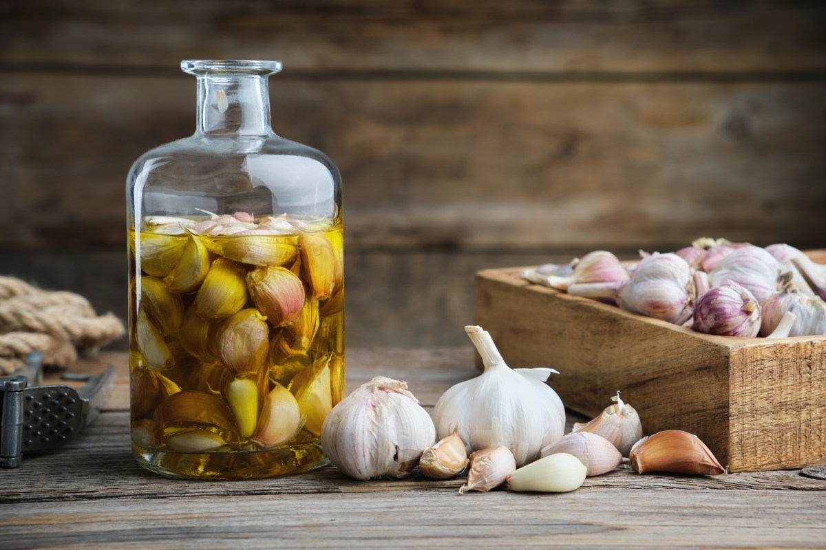 Dientes de ajo enteros infusionandose en aceite de oliva virgen extra para extraer alicina sin fructanos irritantes
