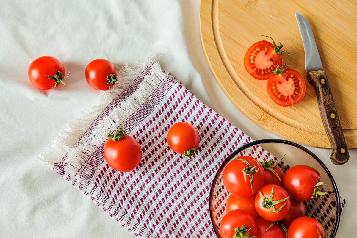 Cuchillo de sierra cortando un tomate siguiendo los tabiques internos para evitar que pierda jugo en la ensalada