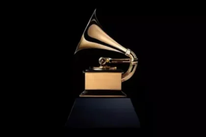 Kendrick Lamar y SZA recibiendo el Grammy 2026 por 'Luther', con trofeo dorado y micrófono en escena iluminada