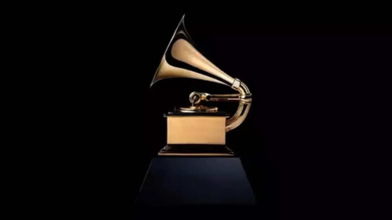 Kendrick Lamar y SZA recibiendo el Grammy 2026 por 'Luther', con trofeo dorado y micrófono en escena iluminada