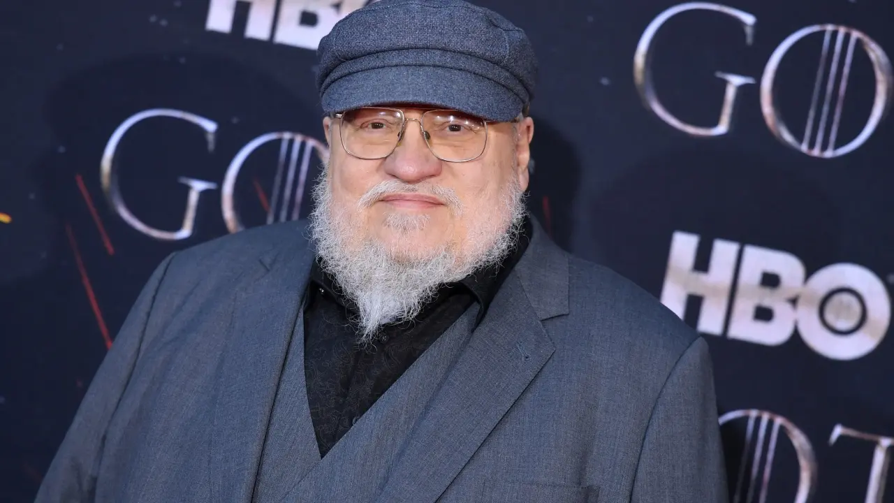 Actor caracterizado como Aerys II Targaryen, el Rey Loco, en una escena teatral oscura con espadas y sombras, revelando su paranoia en Poniente