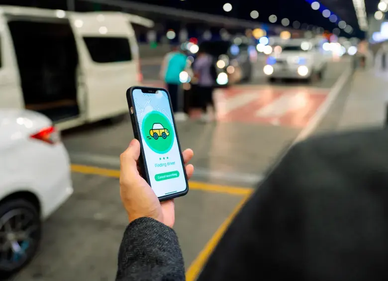 Conductor de Uber revisando su teléfono con expresión de alivio tras el retiro del proyecto de ley que imponía multas de $39 millones por servicio