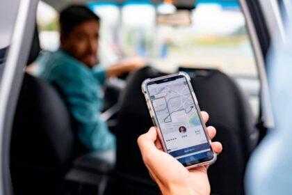Conductor de plataforma de movilidad revisando su teléfono con expresión de preocupación por multas de $4.7 millones por viaje en Colombia