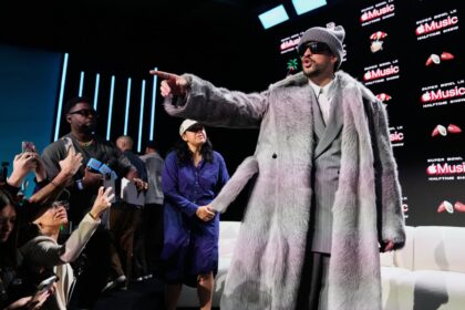 Bad Bunny en el escenario del Super Bowl con luces y público, acompañado de mensajes de apoyo de Katy Perry y Madonna en pantalla gigante