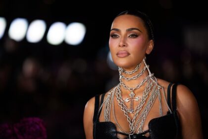 Kim Kardashian y Lewis Hamilton sentados en asientos VIP durante el Super Bowl LX, con expresiones cercanas y sonrisas