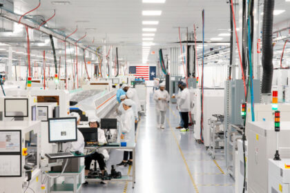 Línea de ensamblaje del Mac mini en la planta de Foxconn en Houston, Texas, con operarios trabajando en componentes tecnológicos