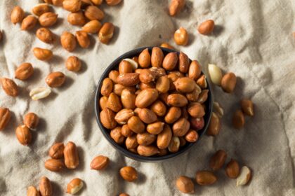 Puñado de maníes tostados con piel sobre superficie de madera, destacando su riqueza en antioxidantes y grasas saludables para cerebro y corazón