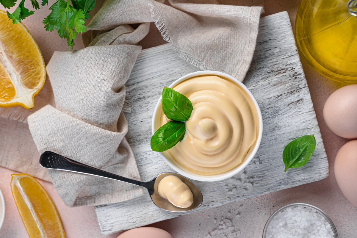 Yema de huevo batiéndose con aceite de oliva virgen extra en mortero para crear una mayonesa casera cremosa y sin cortes