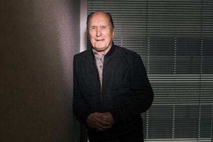 Robert Duvall en su papel de Tom Hagen en 'El Padrino', con traje oscuro y mirada penetrante, símbolo de su legado actoral