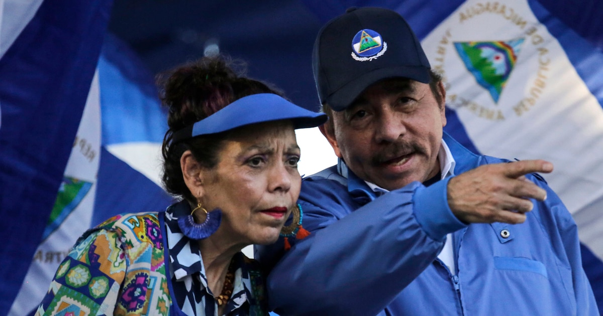 Daniel Ortega y Rosario Murillo en un acto oficial con banderas de Nicaragua, simbolizando el control familiar del poder en medio de represión y exilio masivo