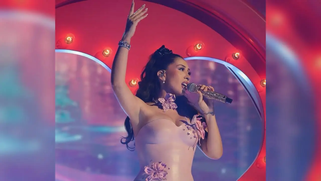 Kali Uchis sonriendo en Bogotá durante su gira The Sincerity Tour, rodeada de seguidores en la Plaza de Bolívar con artesanías colombianas al fondo